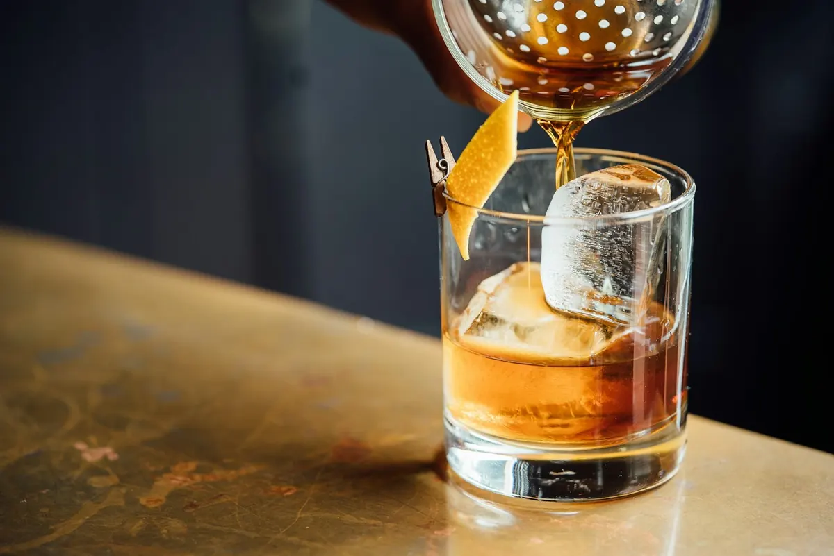 A glass of whisky being poured at the bar